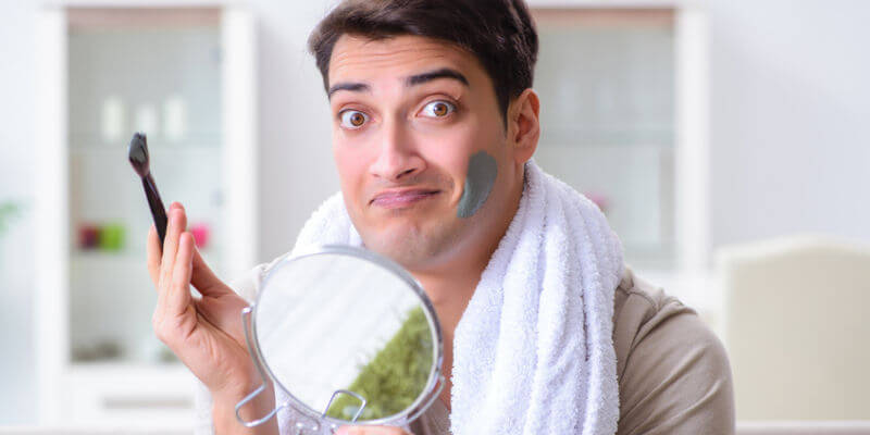 Handsome applying clay mask on face